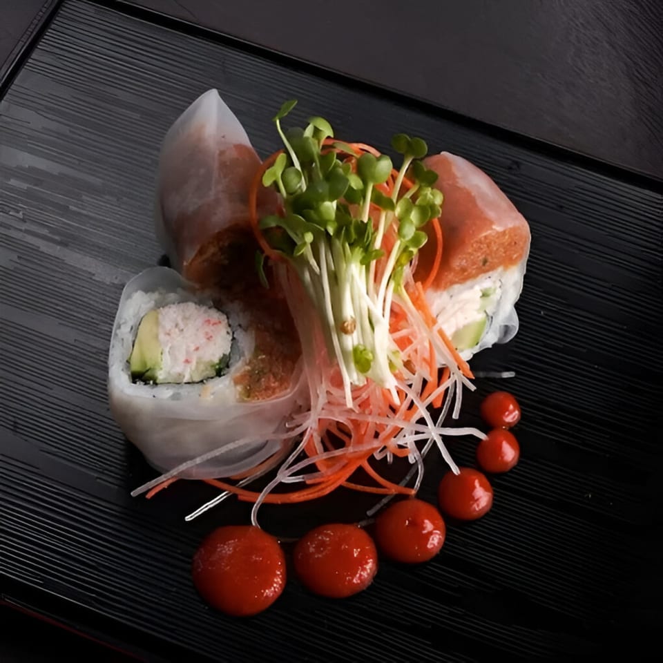 Ohya Sushi's Asian-fusion spring rolls, garnished with sprouts, shredded vegetables, and red sauce dots.